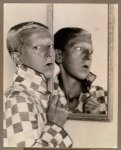 Claude Cahun -- Self-portrait (reflected image in mirror with chequered jacket, 1927).jpg